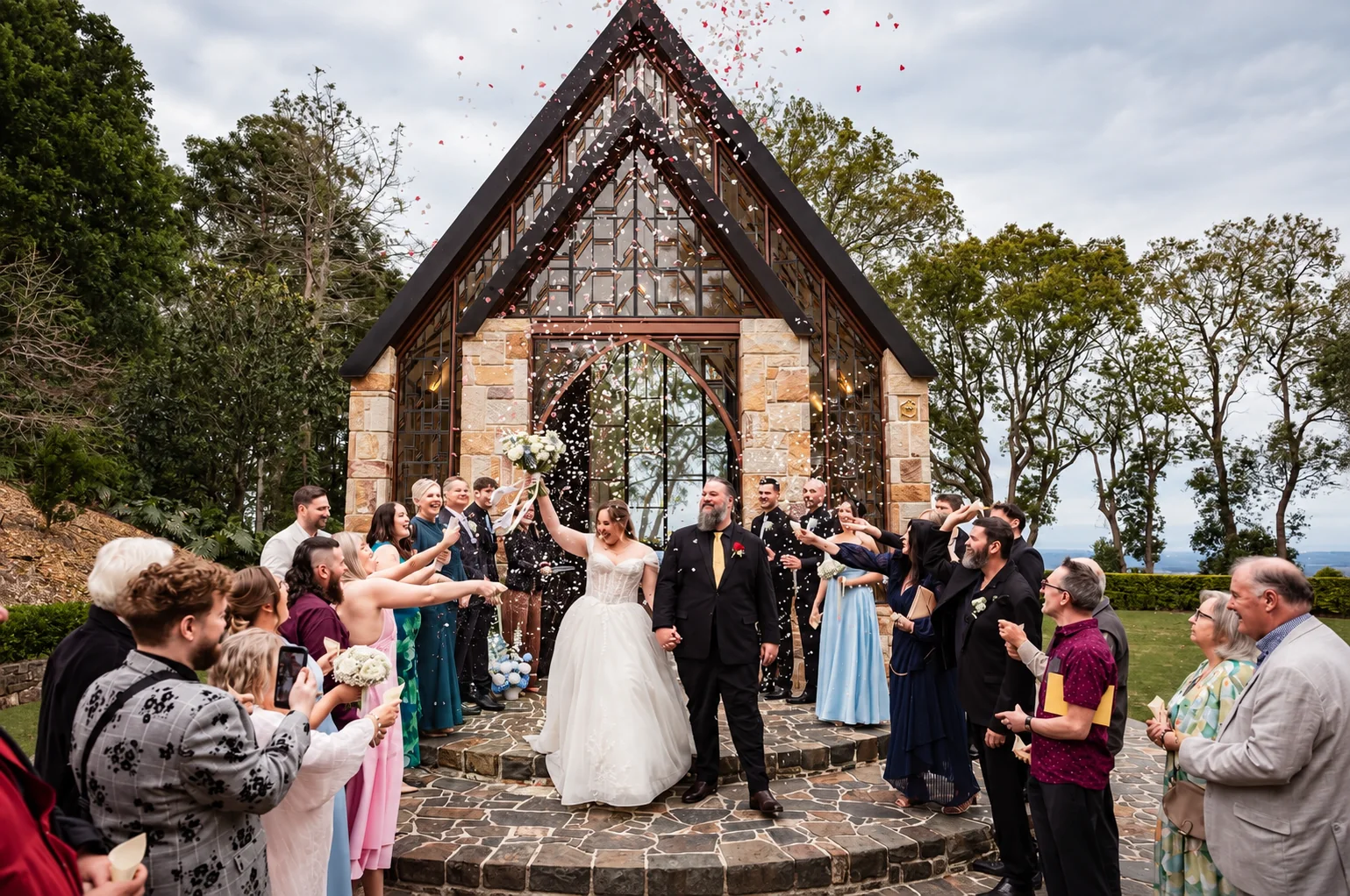 Tricia and Bradley leaving The Chapel Montville beneath falling confetti